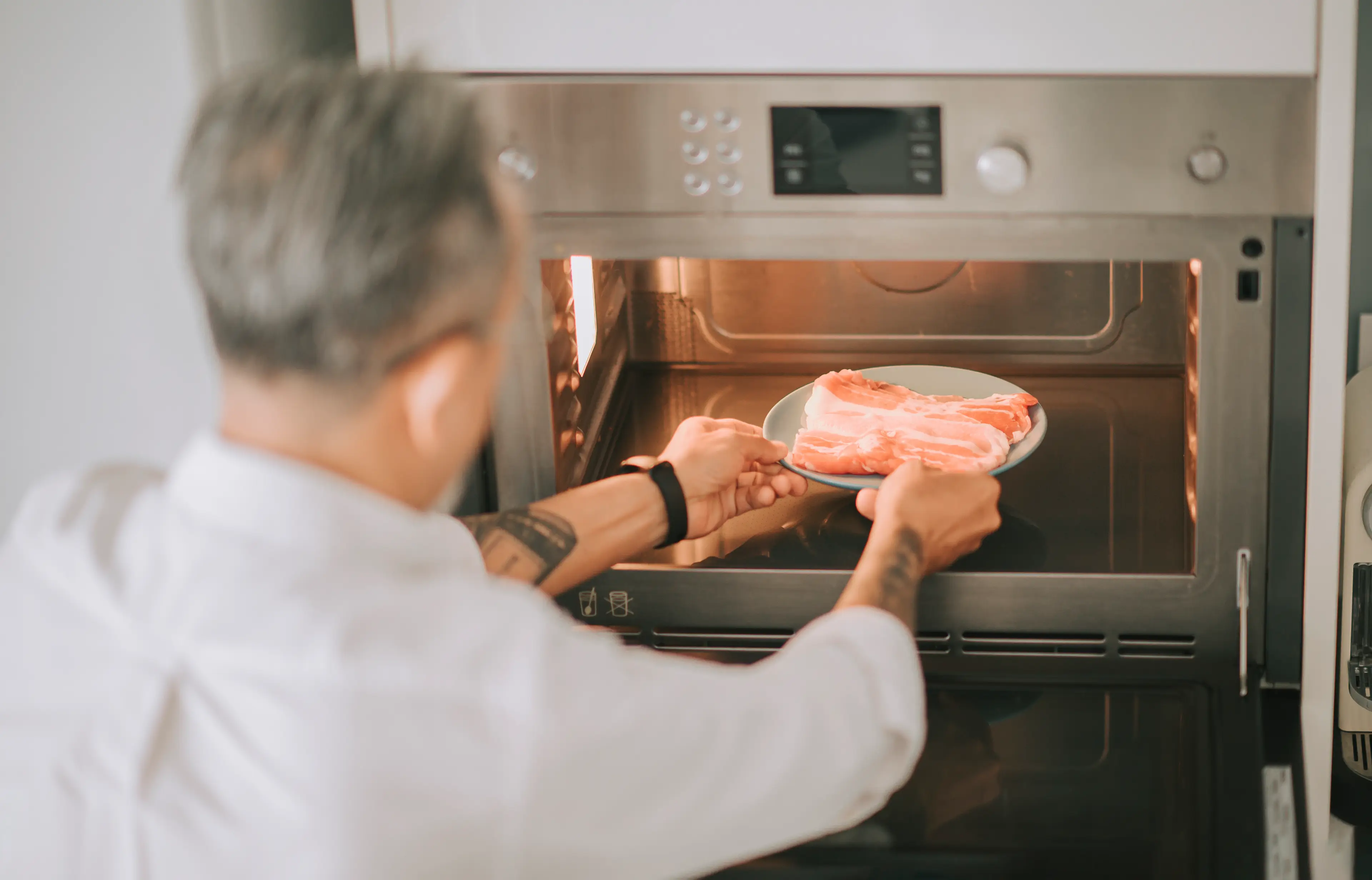Man defrosts meat in a microwave (Edwin Tan via Getty Images)