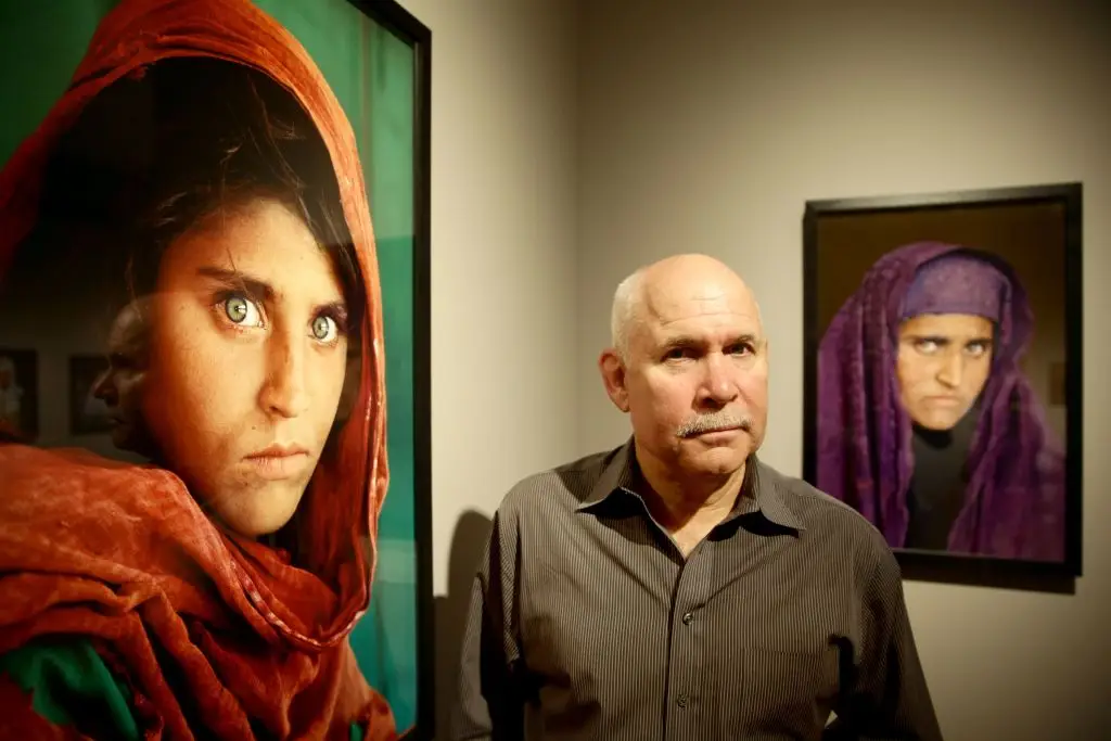 US photographer Steve McCurry next to his photos of Sharbat (ULRICH PERREY / Staff / Getty Images)