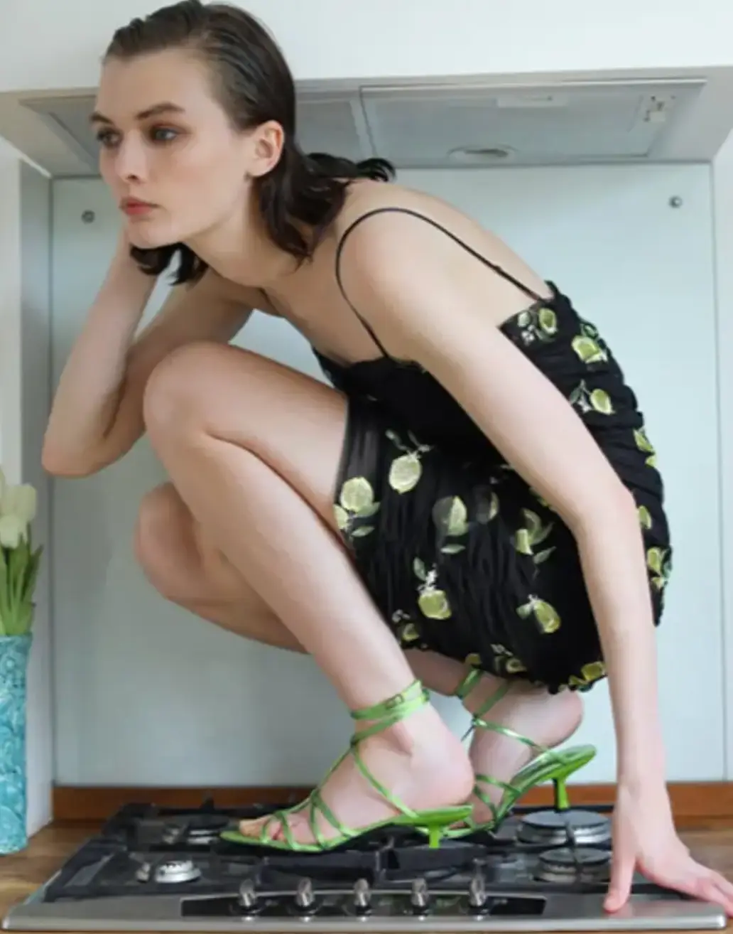 One shot saw a model in strappy green kitten heels inexplicably crouching on a stove top.