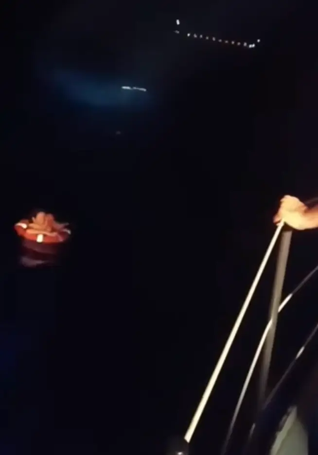 The Coast Guard has shared a video showing a crew throwing a rope to a woman floating in an orange life ring in the dark (YouTube/HellenicCoastguard)