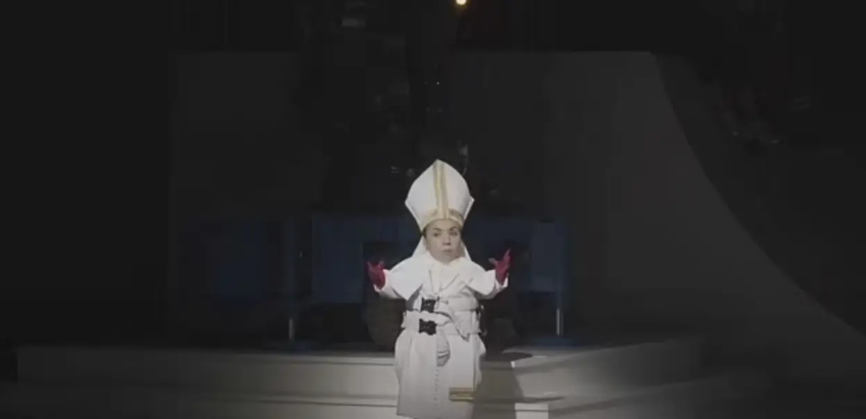 An actress with dwarfism dressed as a nun is swung around my a mechanical arm (YouTube/Staatsoper Stuttgart)