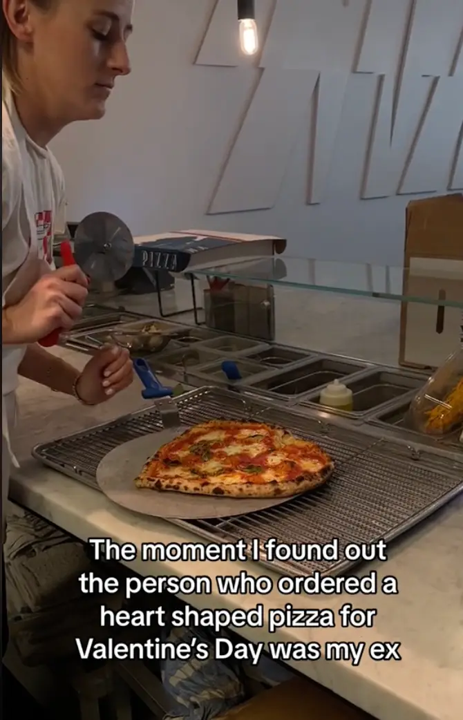 The chef is seen pausing, before completely slicing up a heart shaped pizza.