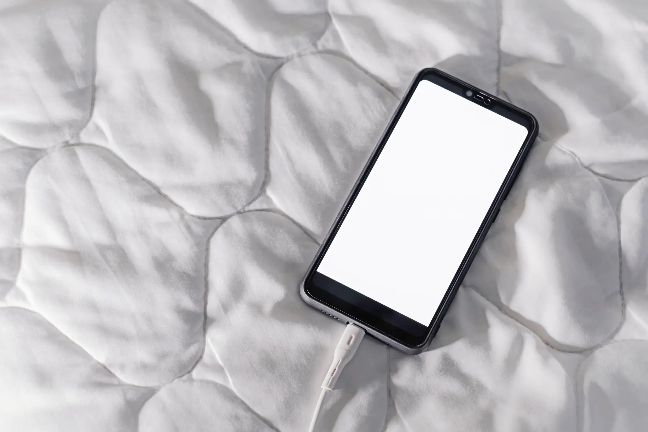 While it might sound dramatic, charging your phone under a duvet or on your bed could cause it to overheat (Getty stock)