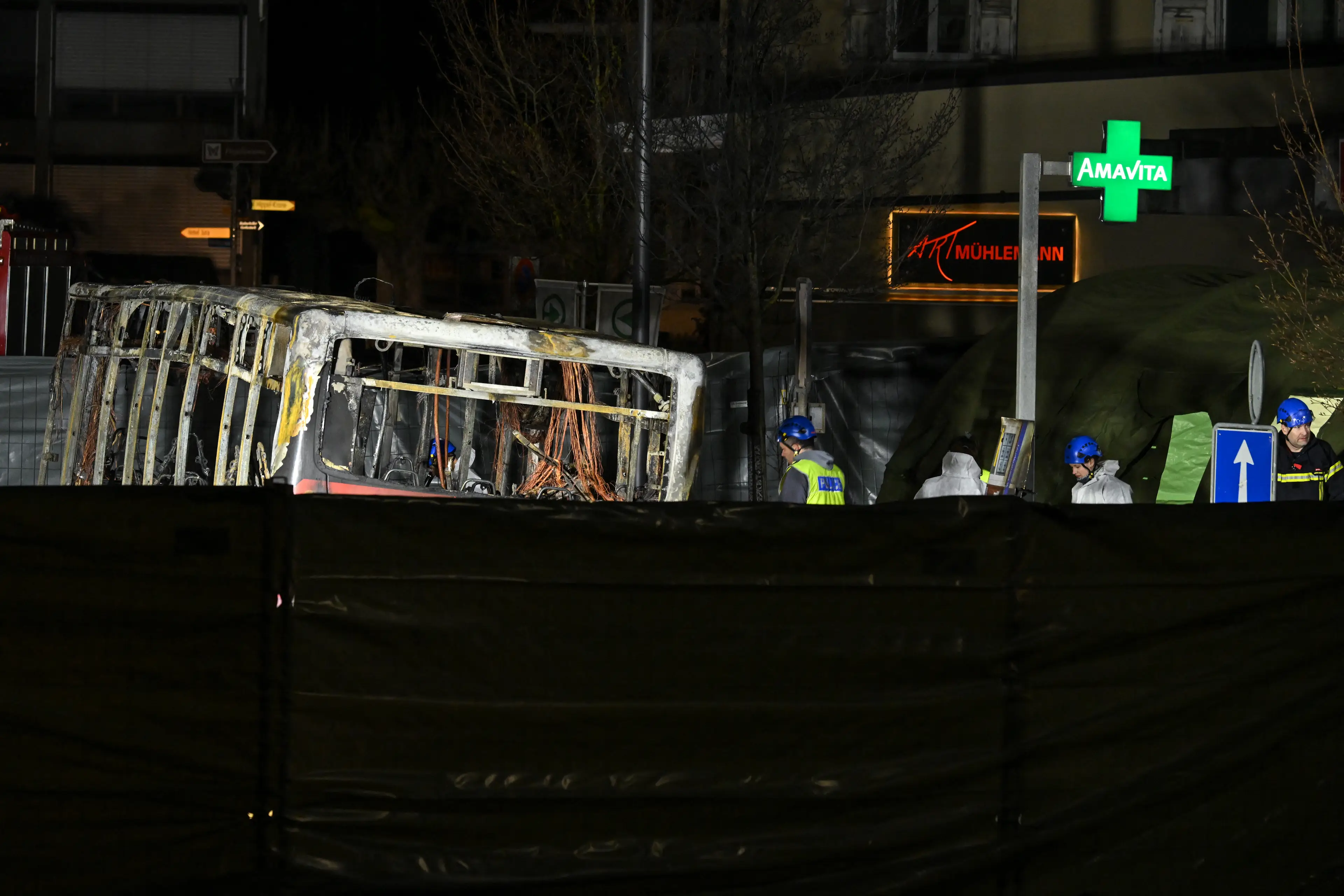 Forensic officers work in a screened-off area inside a bus that caught fire, killing at least six people and injuring five others in what police said may have been a deliberate act. (Fabrice Coffrini / Getty Images)