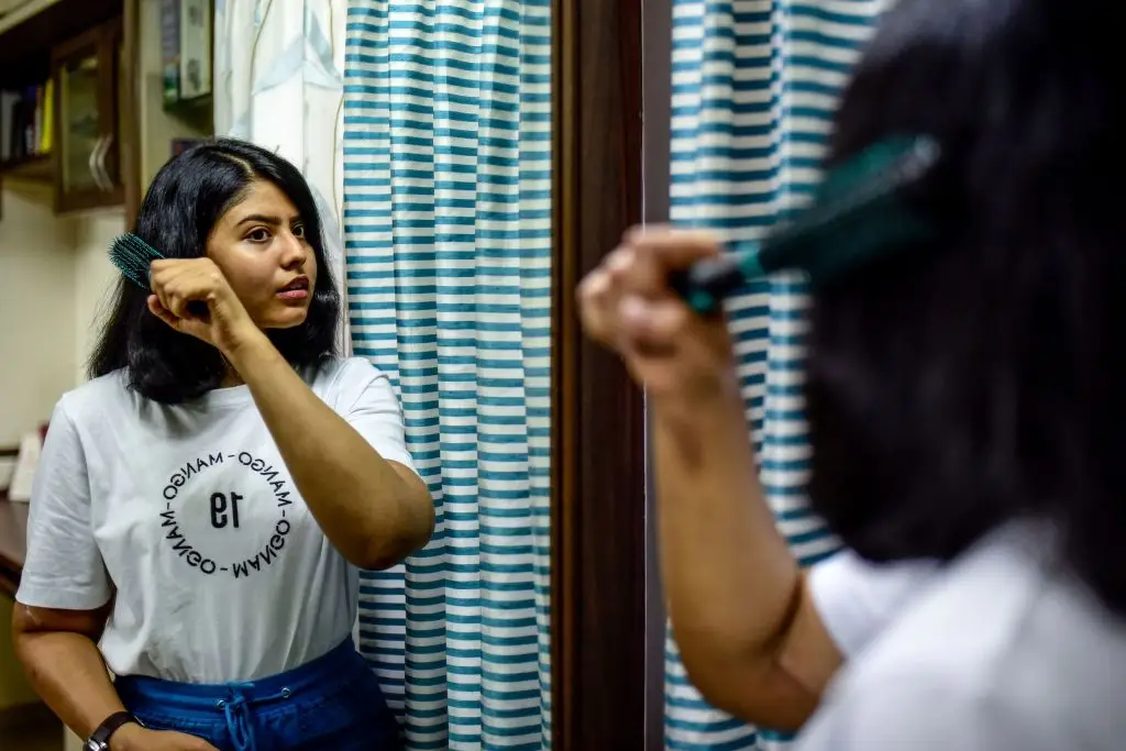 Shreya Siddanagowder brushes her hair in a bathroom at her home in Pune, more than two years after transplant surgery for both hands. (SANKET WANKHADE/AFP via Getty Images)