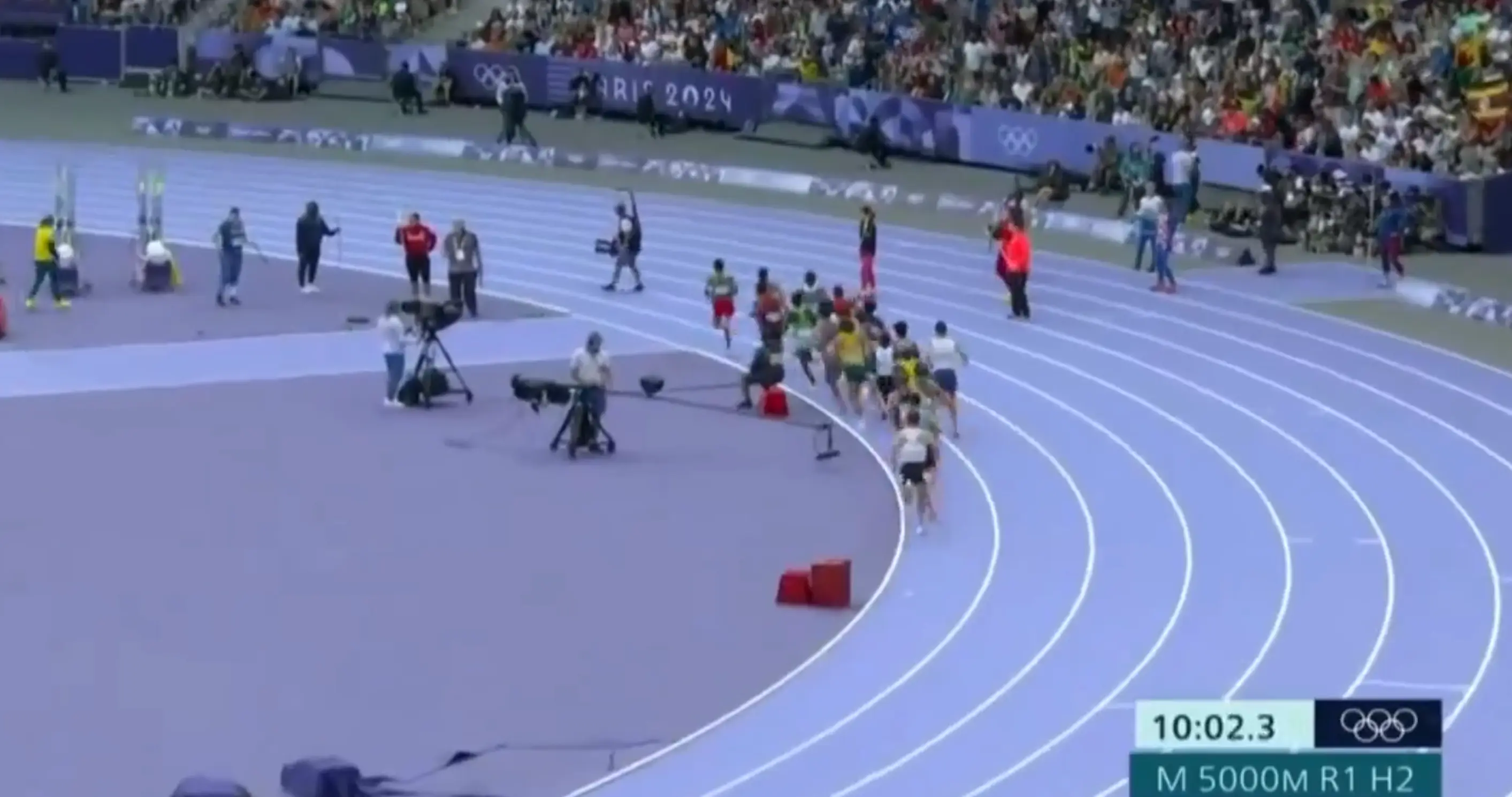 A camera operator casually strolls across the Olympic track while the men's 5,000m race was on. (X/@herrerandres4)