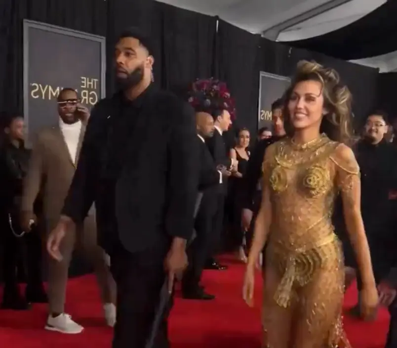 The clip shows Cyrus walking down the red carpet into the ceremony accompanied by her bodyguard who is holding an umbrella.