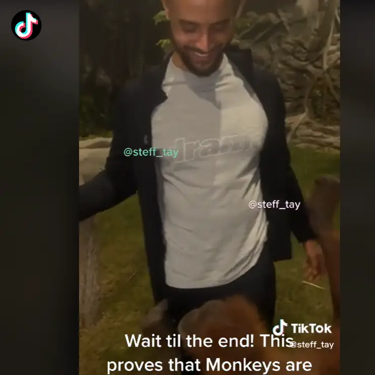 The monkey unzipped the jacket on the man.