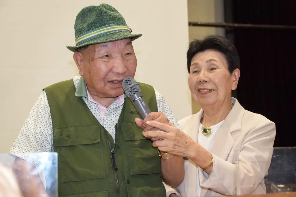 Hakamata speaking as his 91-year-old sister Hideko holds the microphone (STR/JIJI Press/AFP via Getty Images)