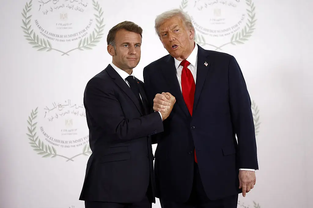 Emmanuel Macron (L) and US President Donald Trump (R) shake hands at the Gaza Peace Summit in Sharm El-Sheikh, Egypt, on October 13, 2025 (Photo by YOAN VALAT/POOL/AFP via Getty Images)