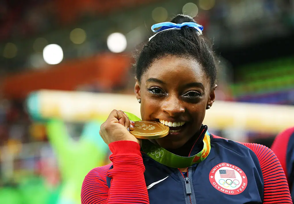 Simone Biles chomping down on her gold medal during the 2016 Olympics in Brazil. (Alex Livesey/Getty Images)