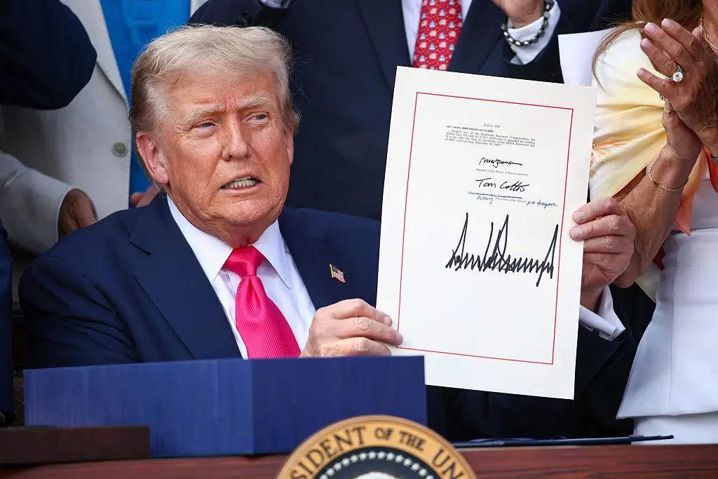 President Donald Trump signs the 'One, Big Beautiful Bill Act' into law during an Independence Day military family picnic (Samuel Corum/Getty Images)