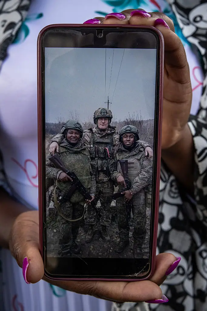 Grace Gathoni Kagombe, 37, holds up a photo of her husband, Kenyan Martin Macharia Mburu, (left) who was killed in action fighting for Russia (Getty)