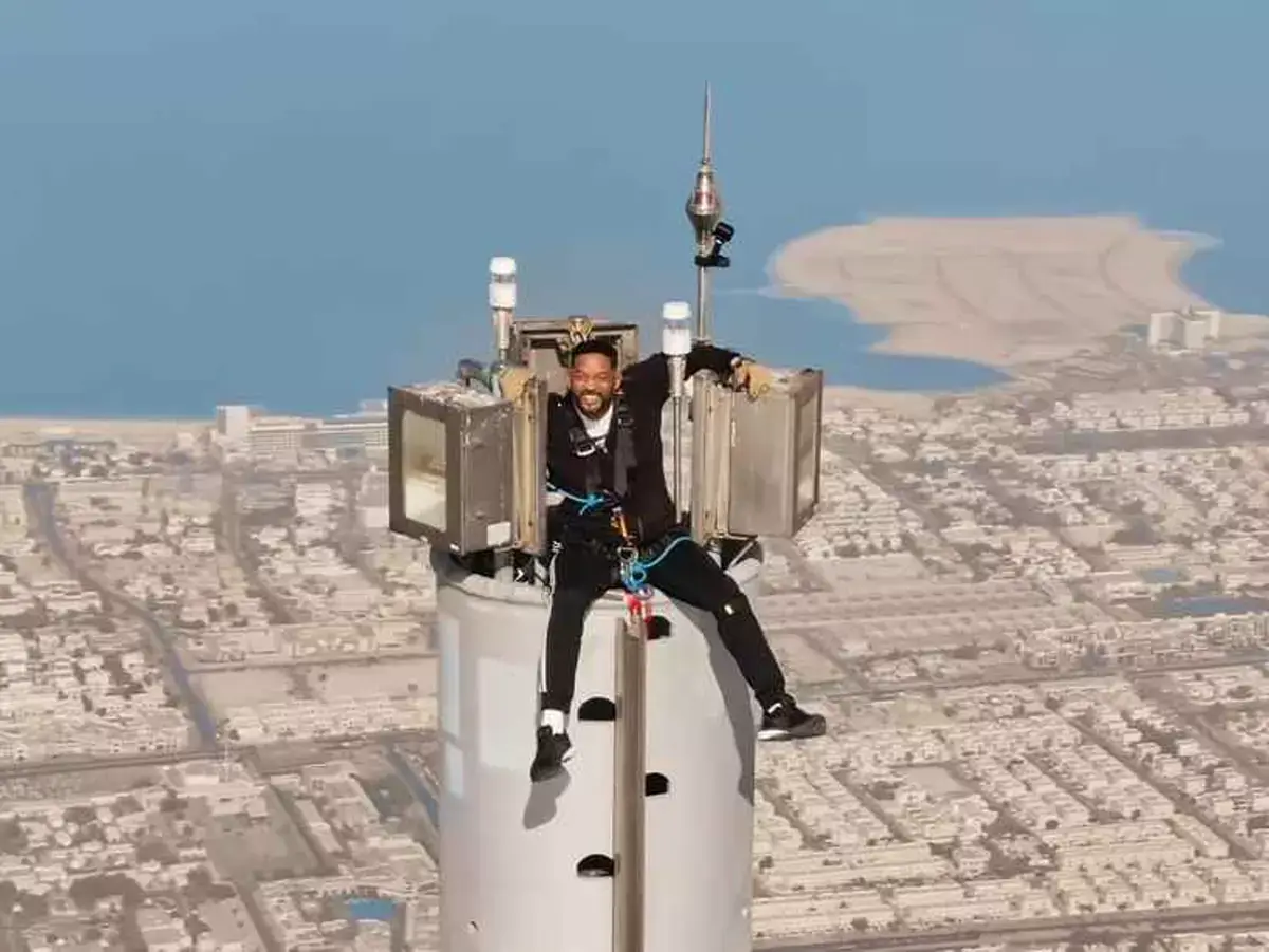 Will Smith grips tightly onto the tip of the Burj Khalifa with a grimace on his face - stark contrast to Cruise's almost effortless pose (YouTube)