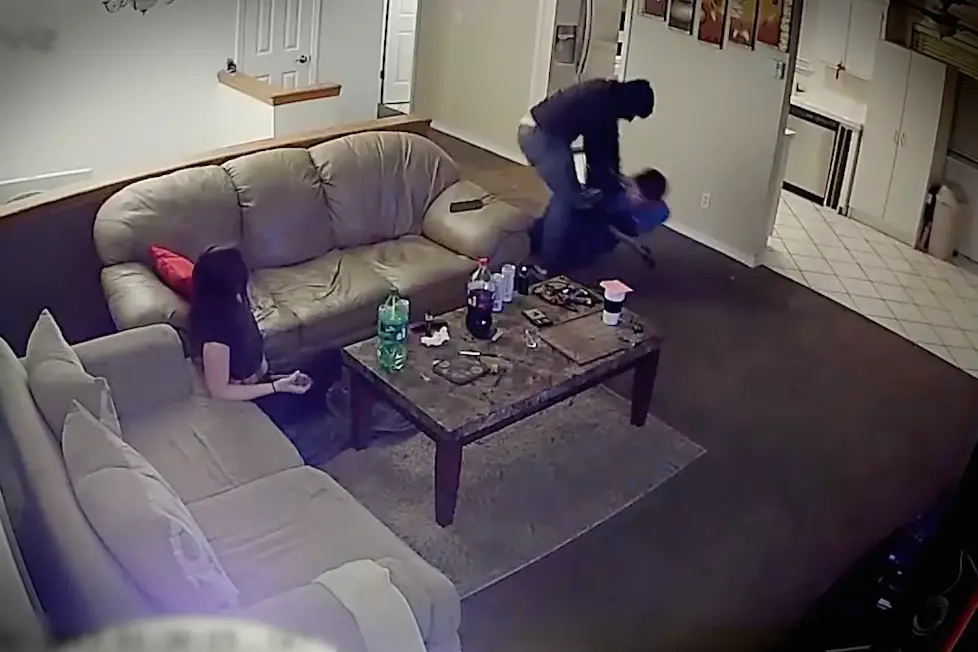 Caspian grabs the barrel of the intruder's shotgun and holds on as he is dragged out of the building.