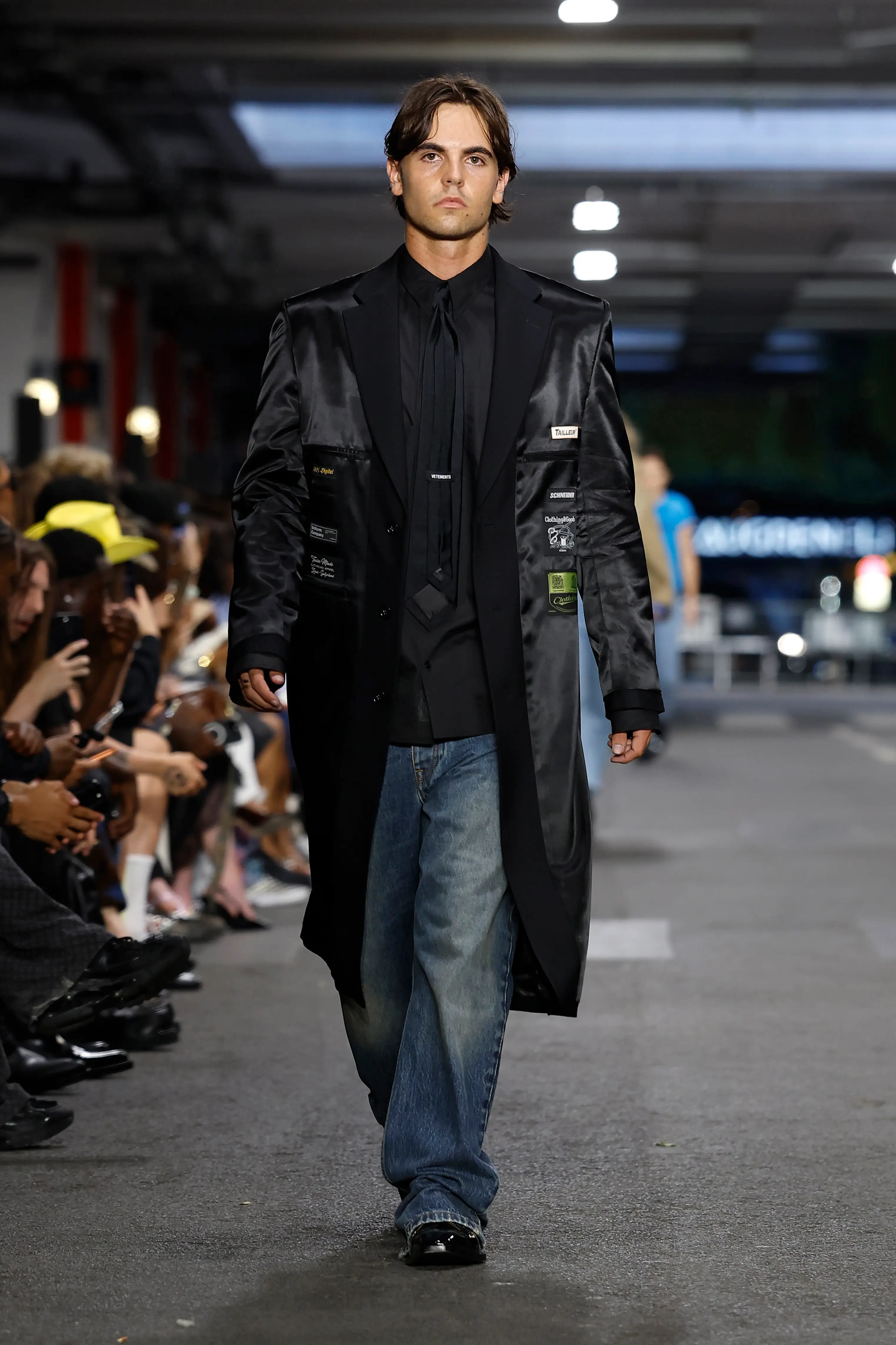 Sean Preston walked in a long black silk jacket paired with a monochromatic black shirt and tie, jeans, and shiny black shoes (Photo by Estrop/Getty Images)