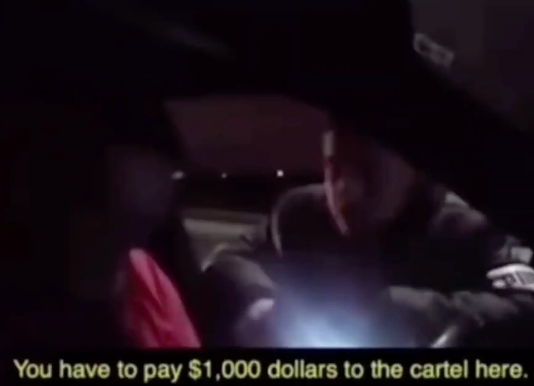 The cartel member shines a torch light into the car and another man is seen walking on the roadside with him.