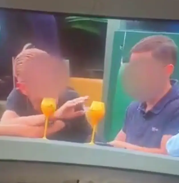 The tennis fan was spotted reaching for something in his lap.