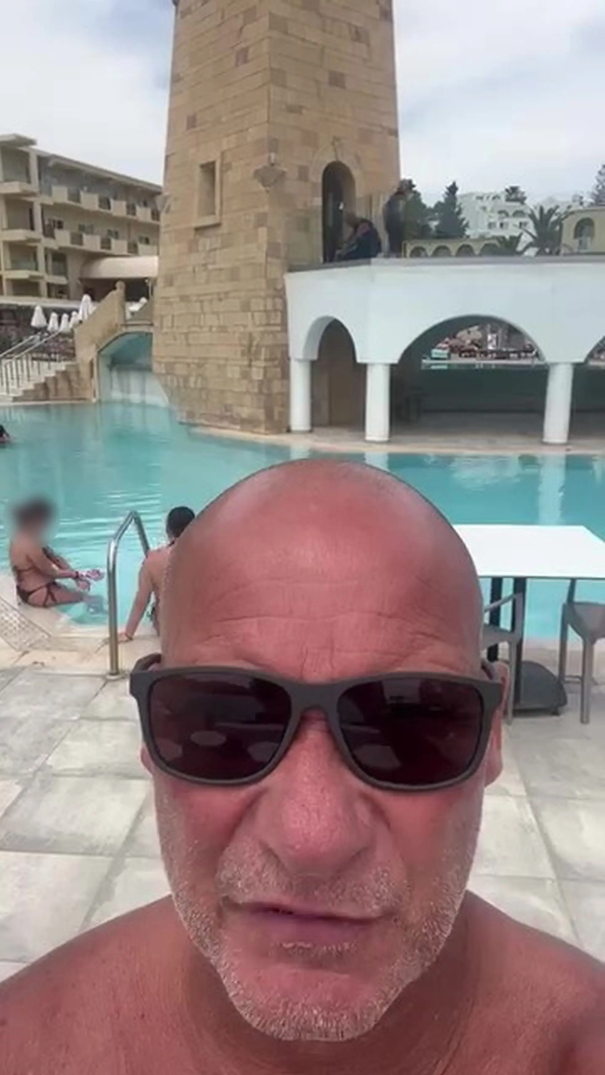 Construction workers can be seen working above the pool while holidaymakers took a dip (Kennedy News and Media)