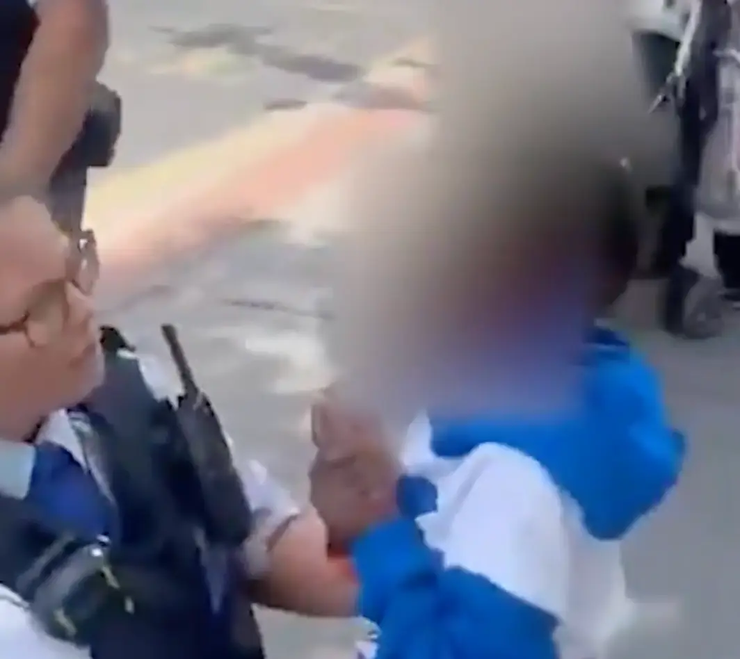 The woman struggled as she was held by the officers.