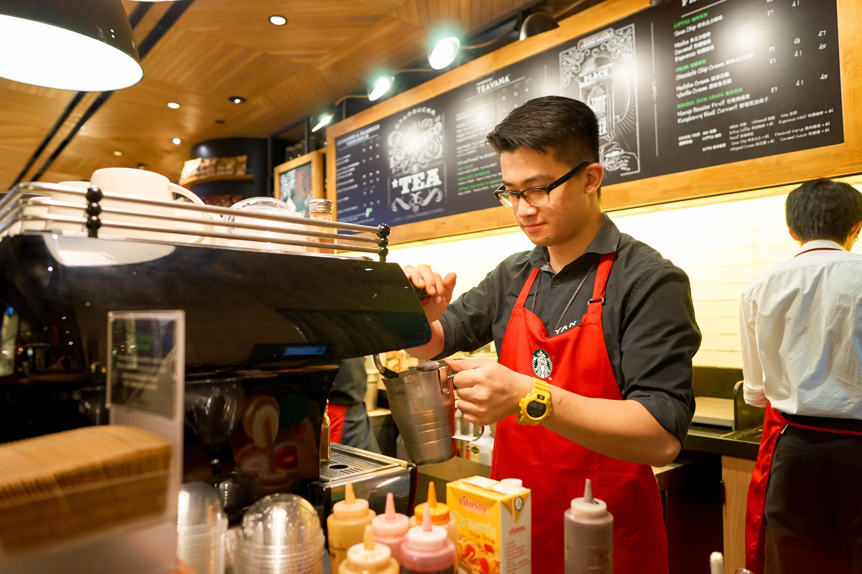 A Starbucks worker in a red apron.