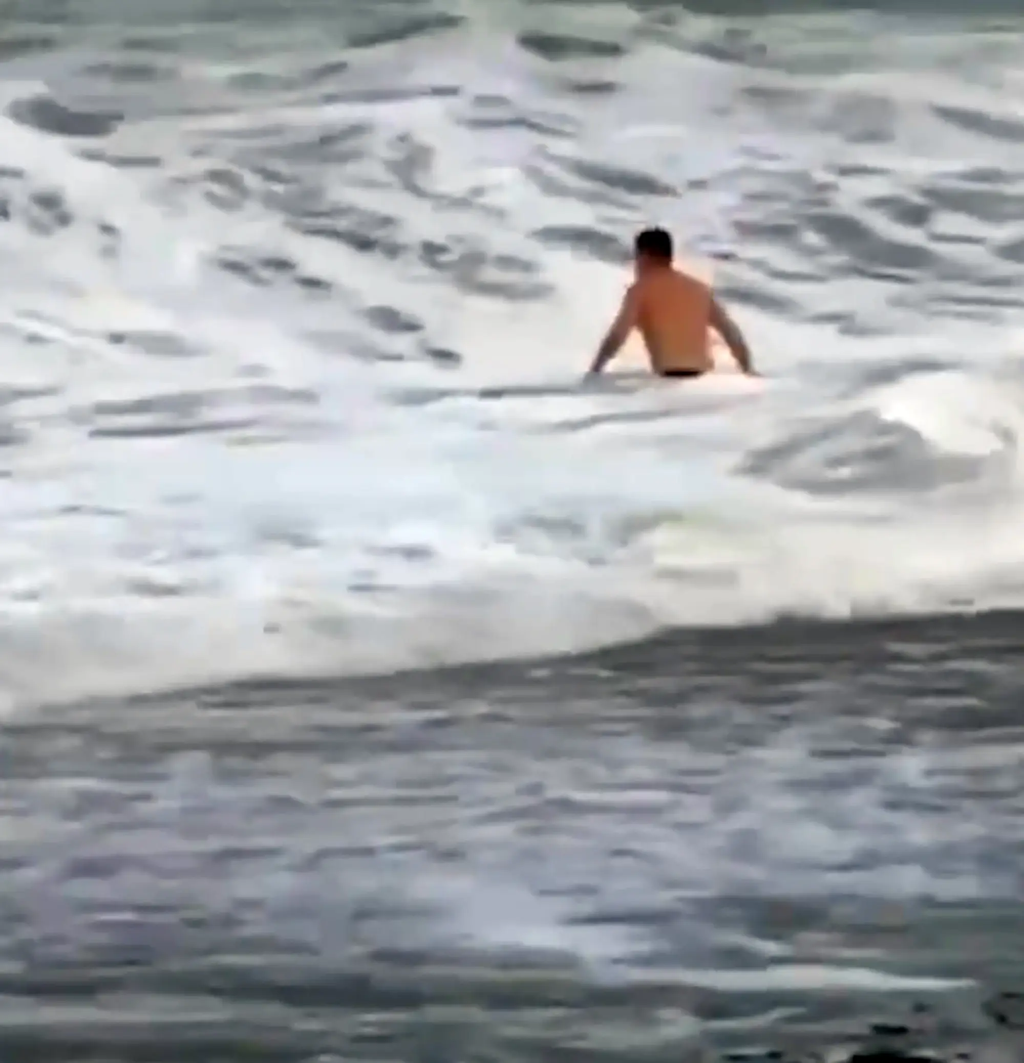 The man can be seen looking for his girlfriend when she disappears under the waves. (Newsflash)