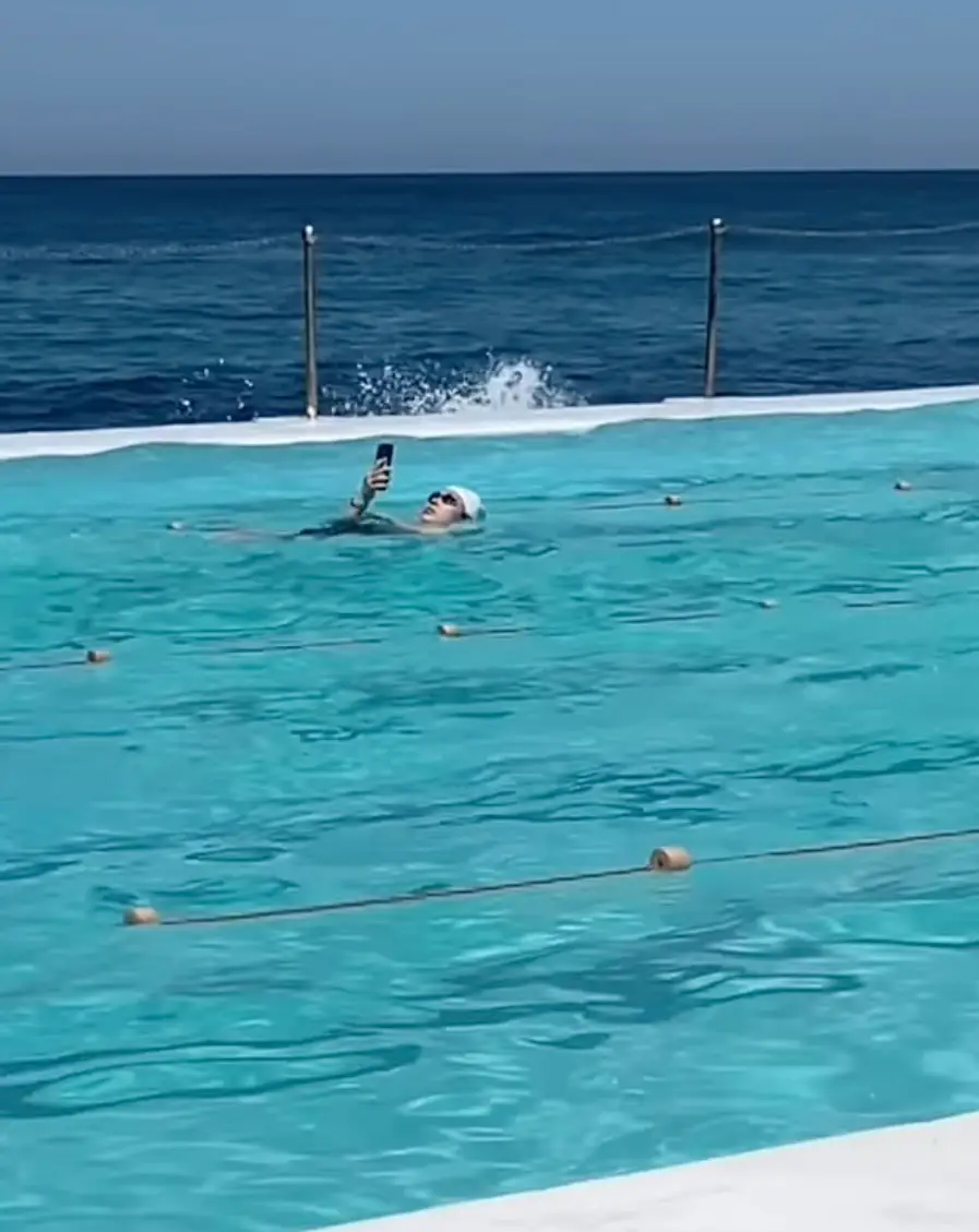 The mystery swimmer was seen scrolling in the pool in the viral video (Instagram/@browncardigan)