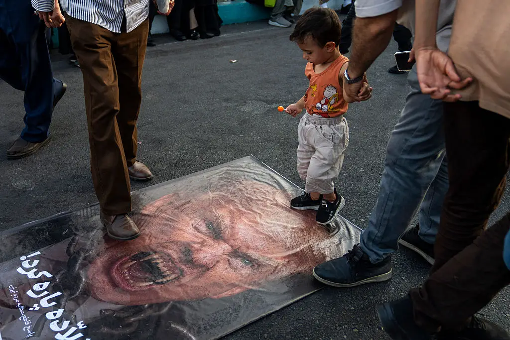 Iranian protestors pictured stamping on a picture of Donald Trump with vampire fangs (Getty Images)
