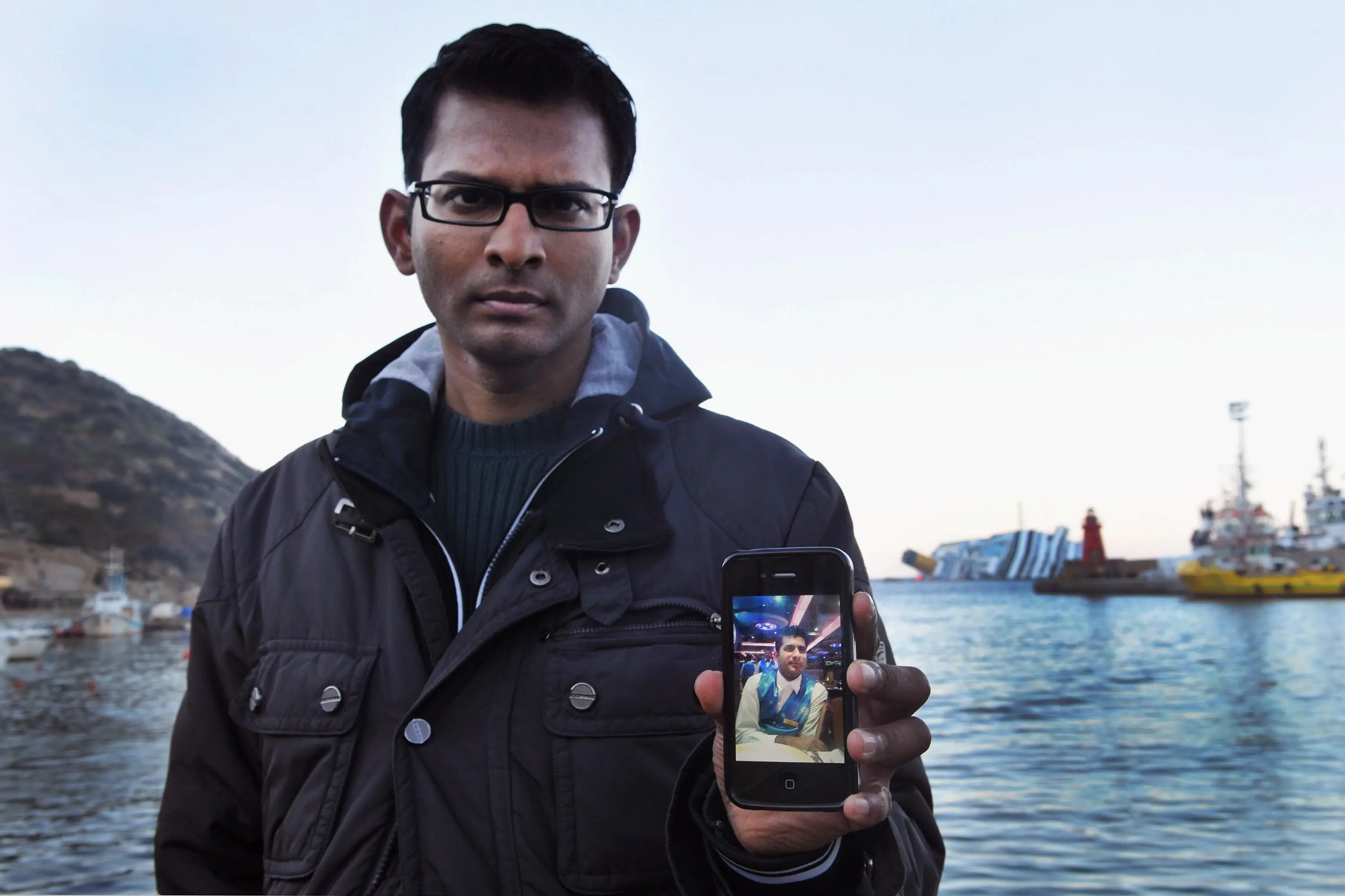 Kevin Rebello holding a photo of his brother Russel while waiting for him to be found. (Laura Lezza/Getty Images)