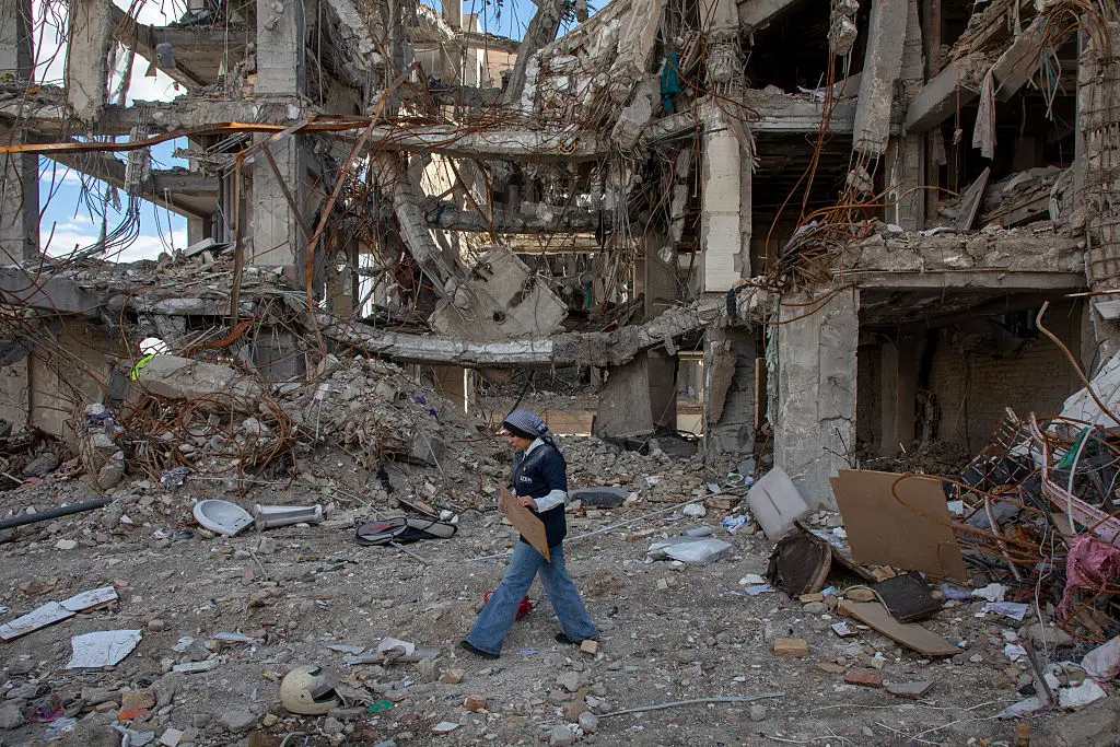 A woman walks through ruins in Tehran on Monday following US and Israeli strikes (Majid Saeedi/Getty Images)