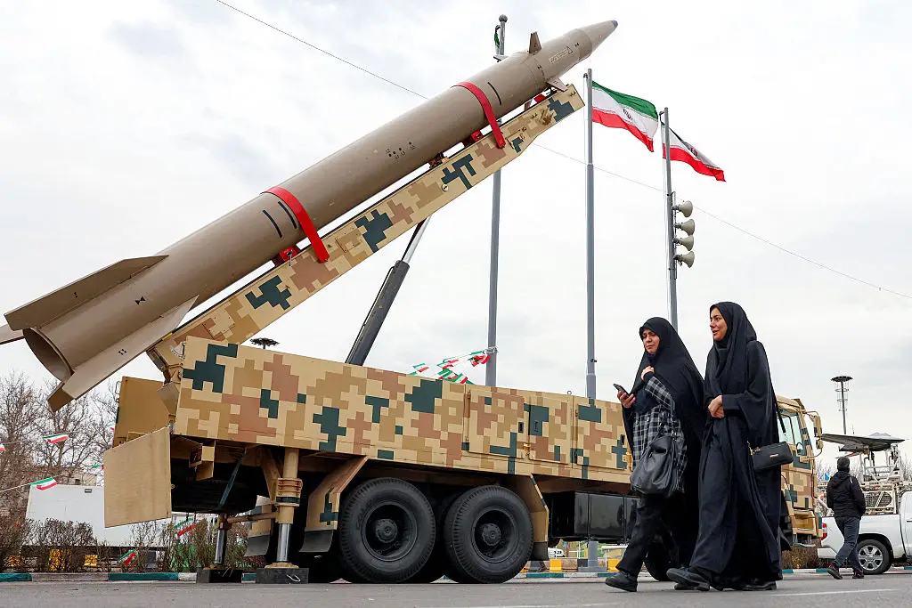 Women walk past a ballistic missile launch vehicle in Tehran (Getty)