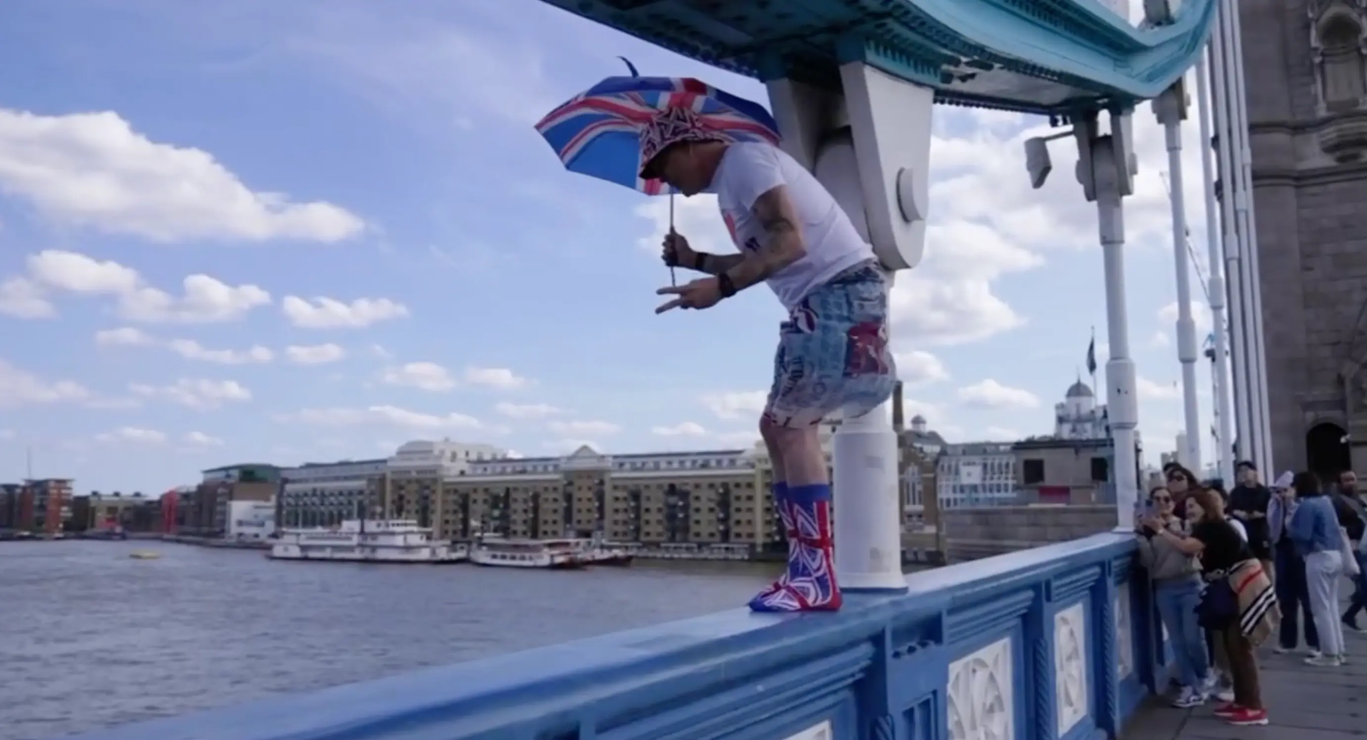 Steve-O standing on the railings at Tower Bridge.