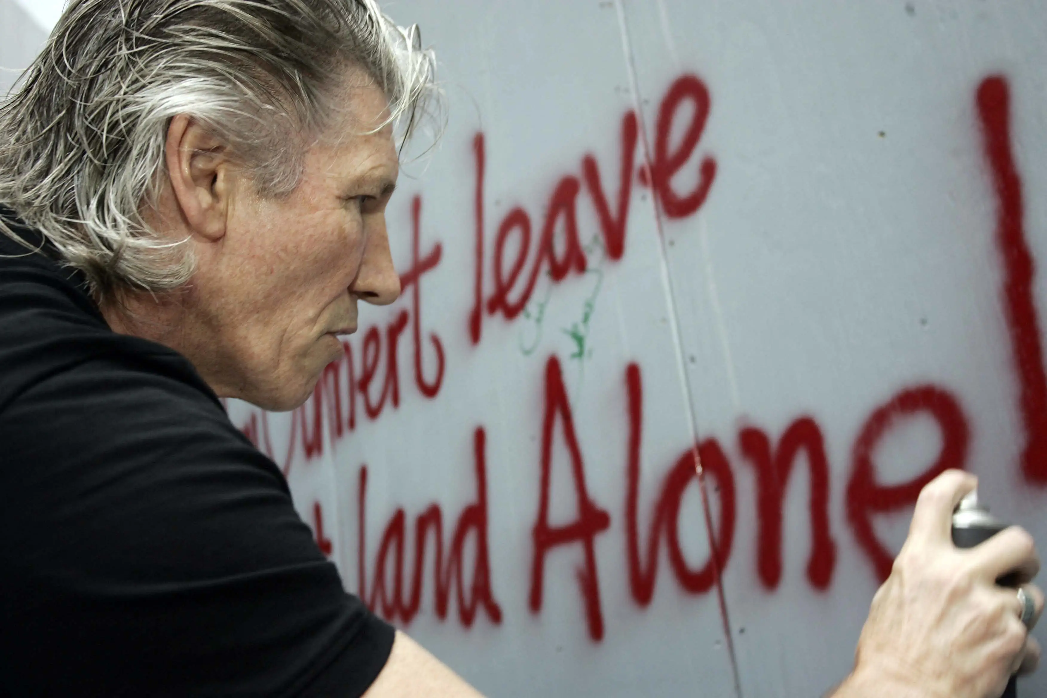 The Brit rocker seen spray painting on Israel's separation barrier surrounding the West Bank town of Bethlehem in July 2006 (ROB KEERIS/ANP/AFP via Getty Images)