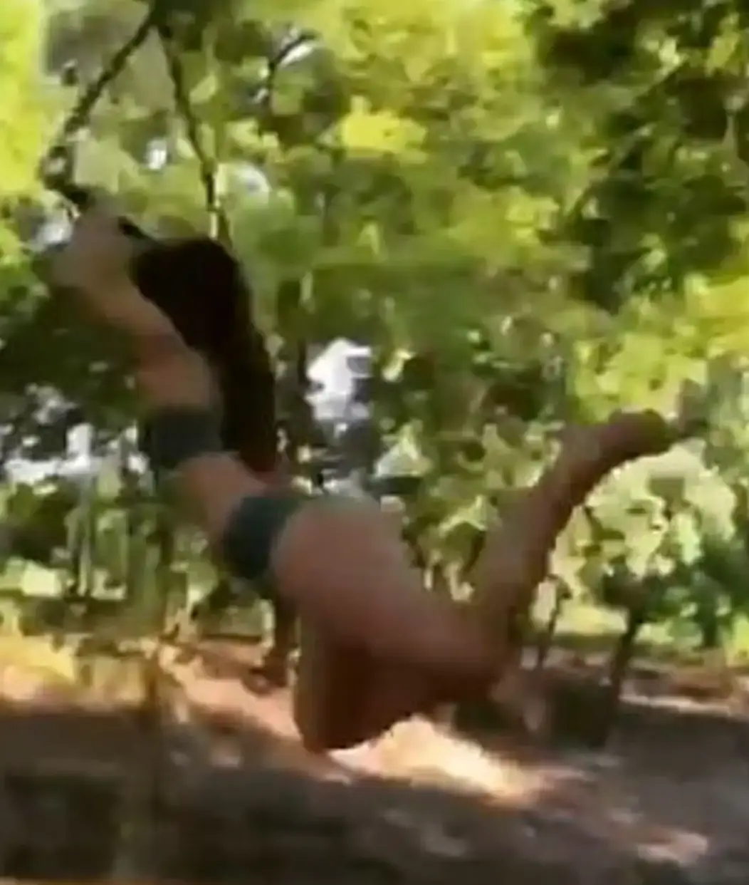 The woman appears to hit an invisible object as she leaps from the swing.