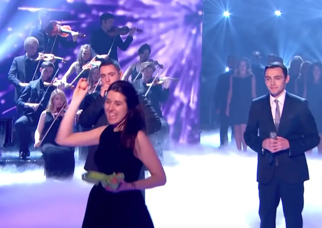 In the midst of their 2013 final performance, singers Richard and Adam Johnson were unsurprisingly unshaken when a violinist named Natalie Holt emerged from the orchestra behind them - with what looked like a half dozen eggs in her hand.