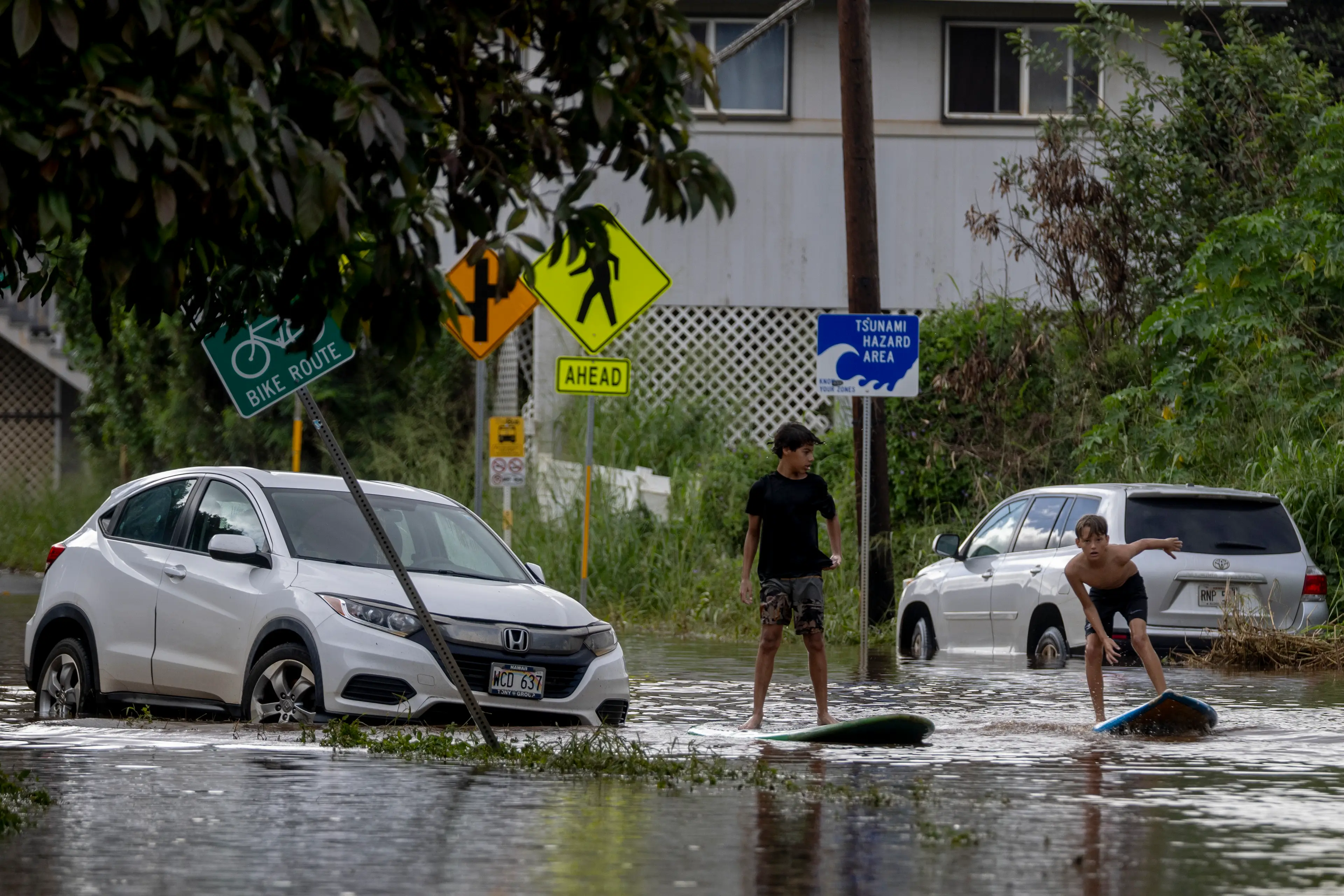 Teens in Waialua, Hawaii, seen surfing through the floodwater this weekend (Stephen Lam/San Francisco Chronicle via Getty Images)