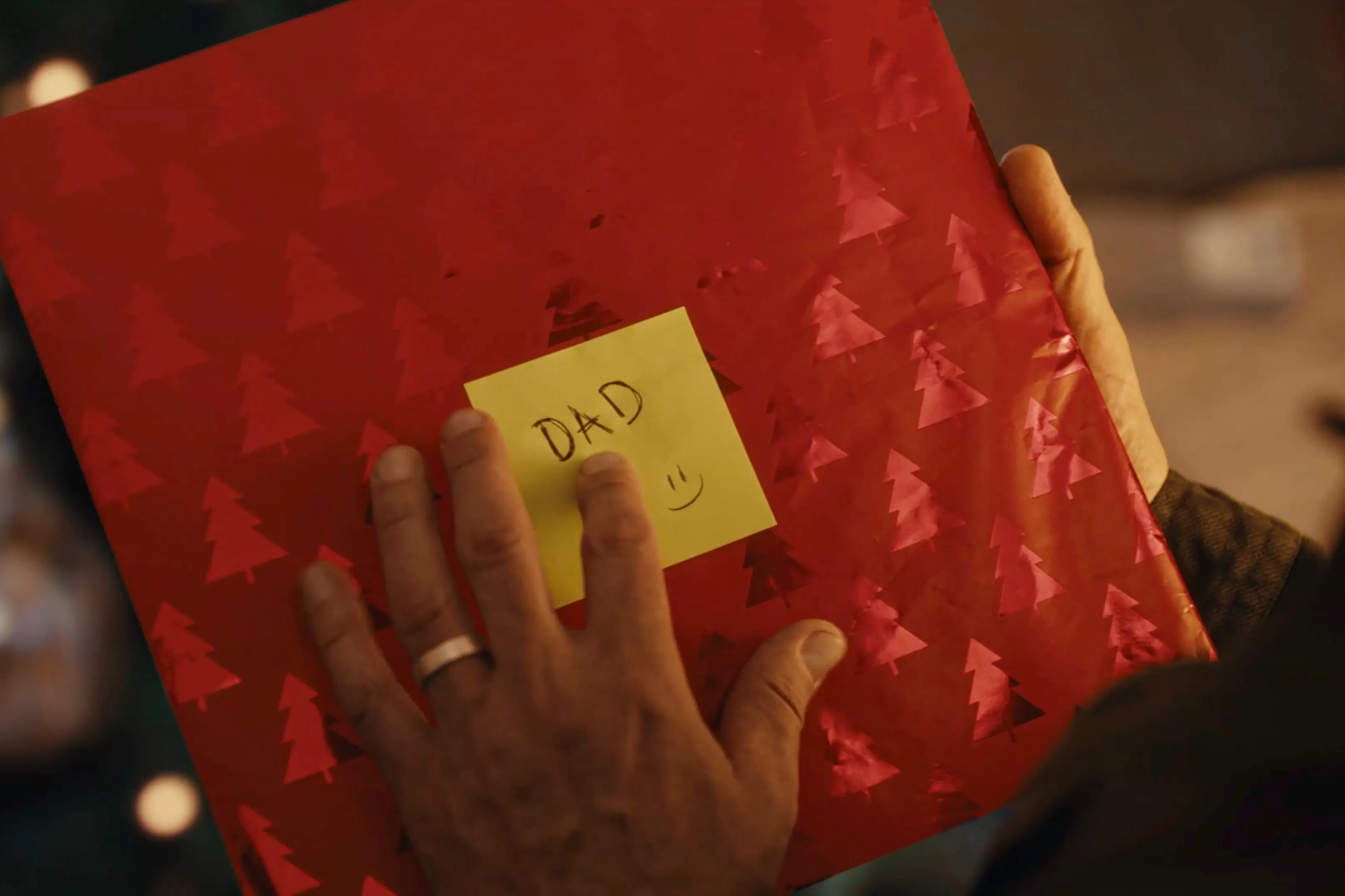 The dad is shifting through the disregarded wrapping paper when he finds the gift (John Lewis)