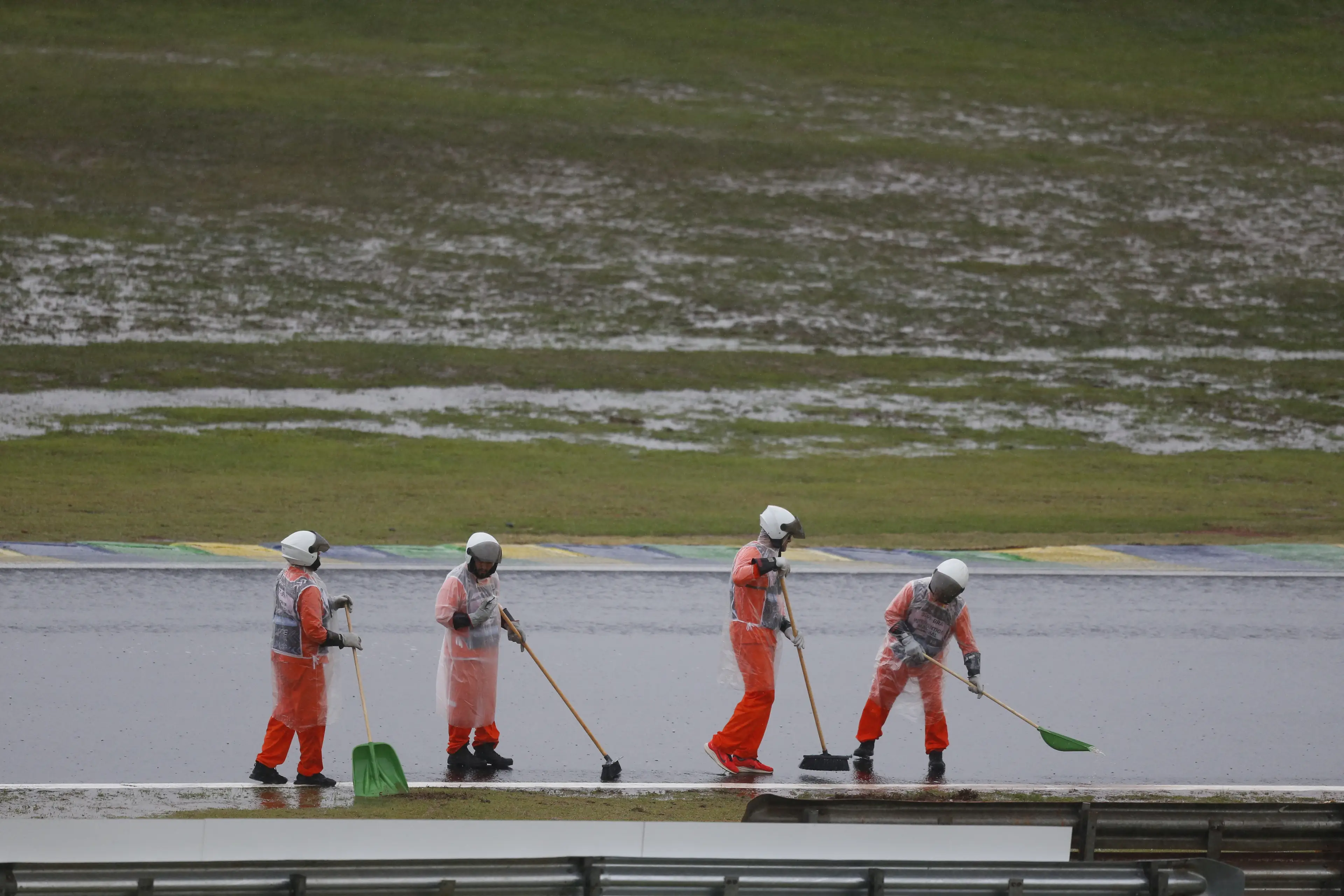 Marshals sweep the track after heavy rainfall. Image: Getty 