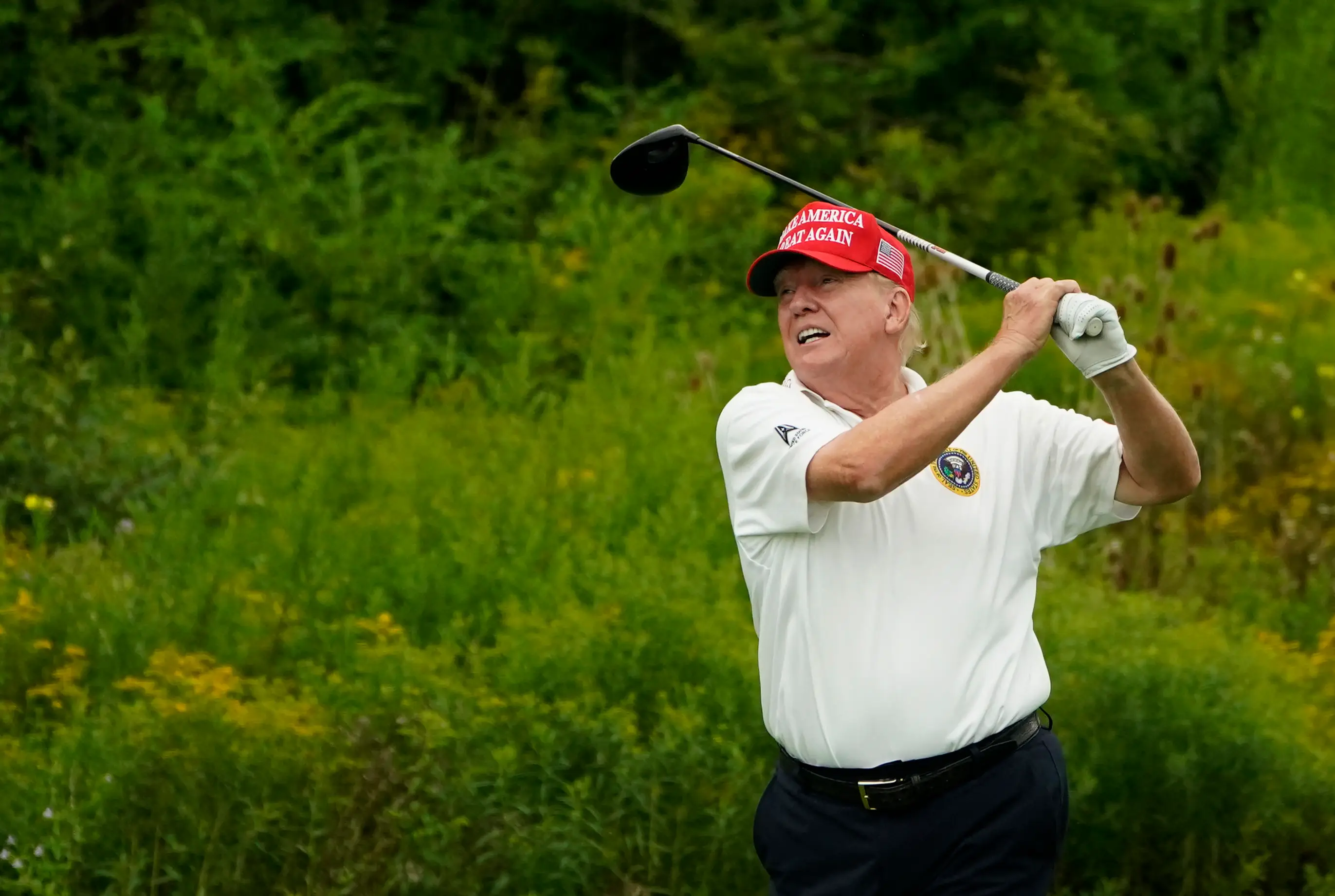 Donald Trump mid-swing on a golf course. Image: Getty