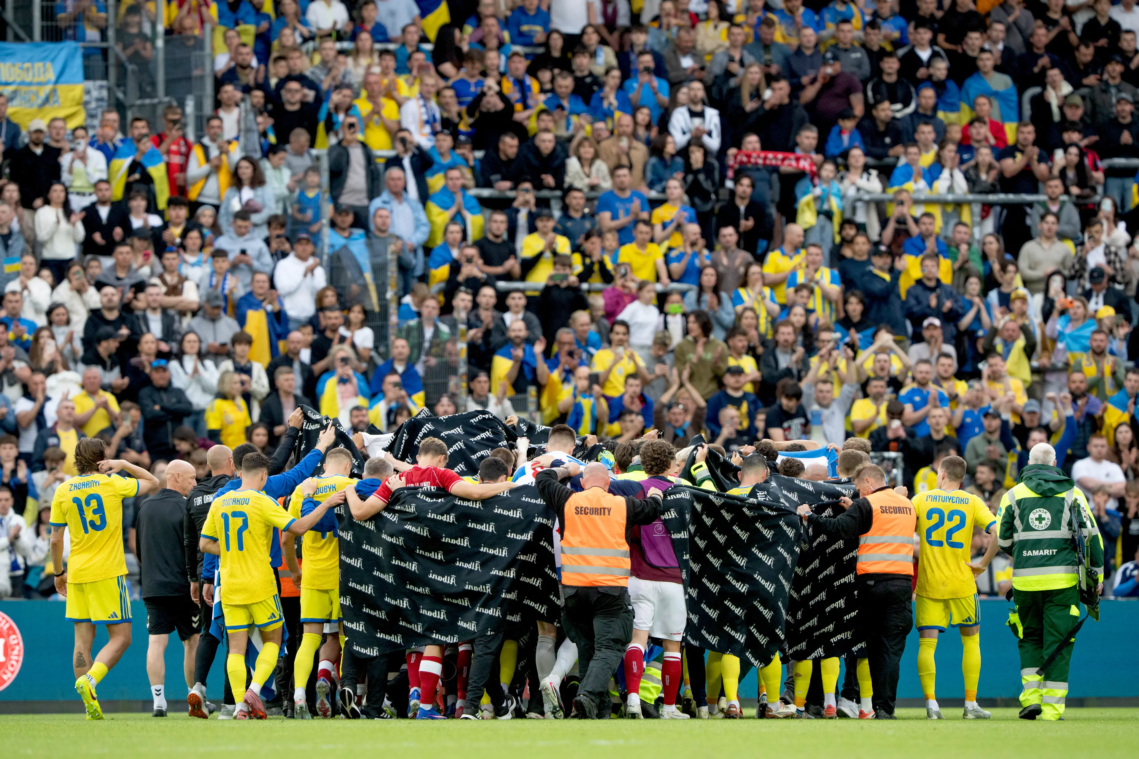 Denmark and Ukraine players huddle around Denmark midfielder Christian Eriksen. Image credit: Getty