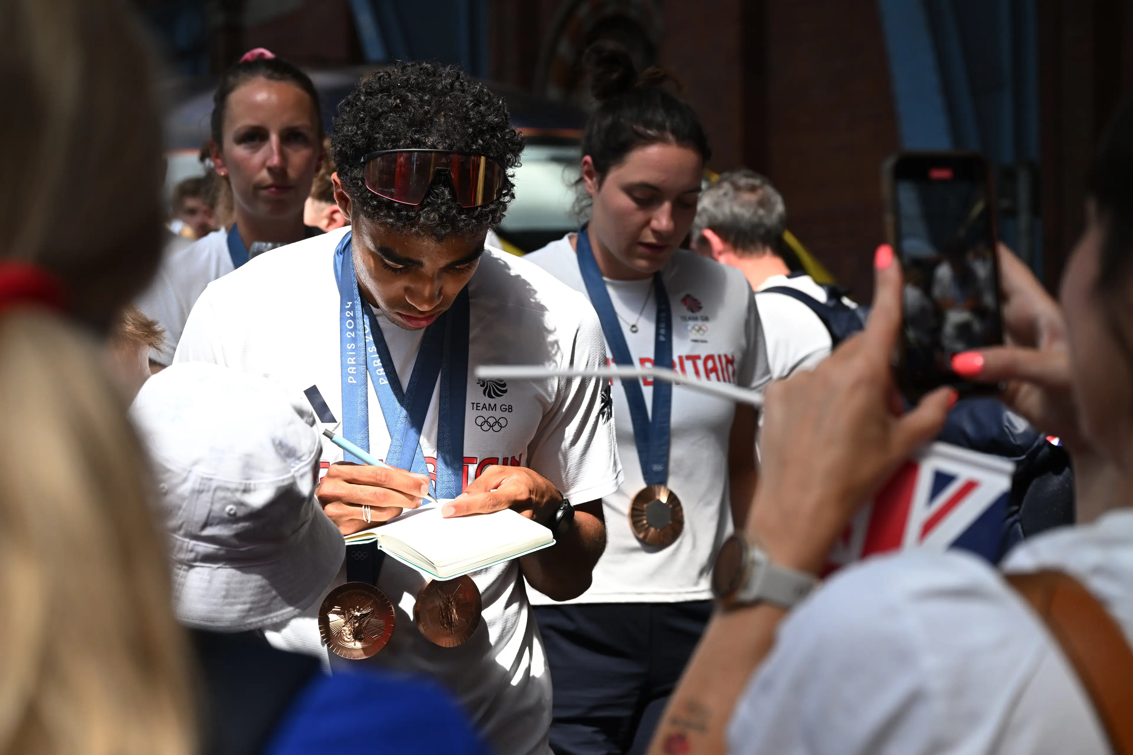 Sam Reardon signs autographs after arriving back in the UK