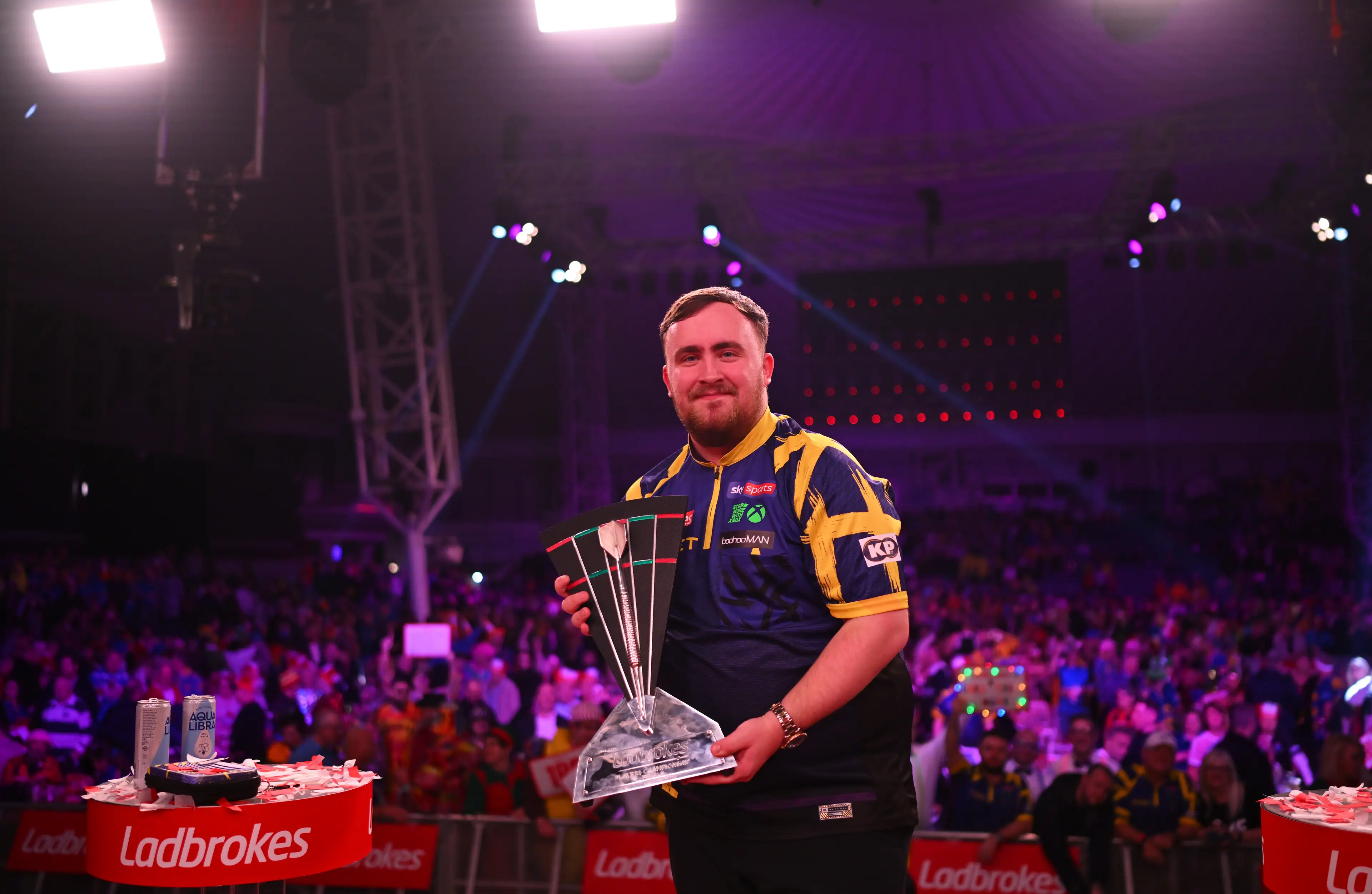 Luke Littler poses with the Players Championship Finals trophy. Image credit: Getty