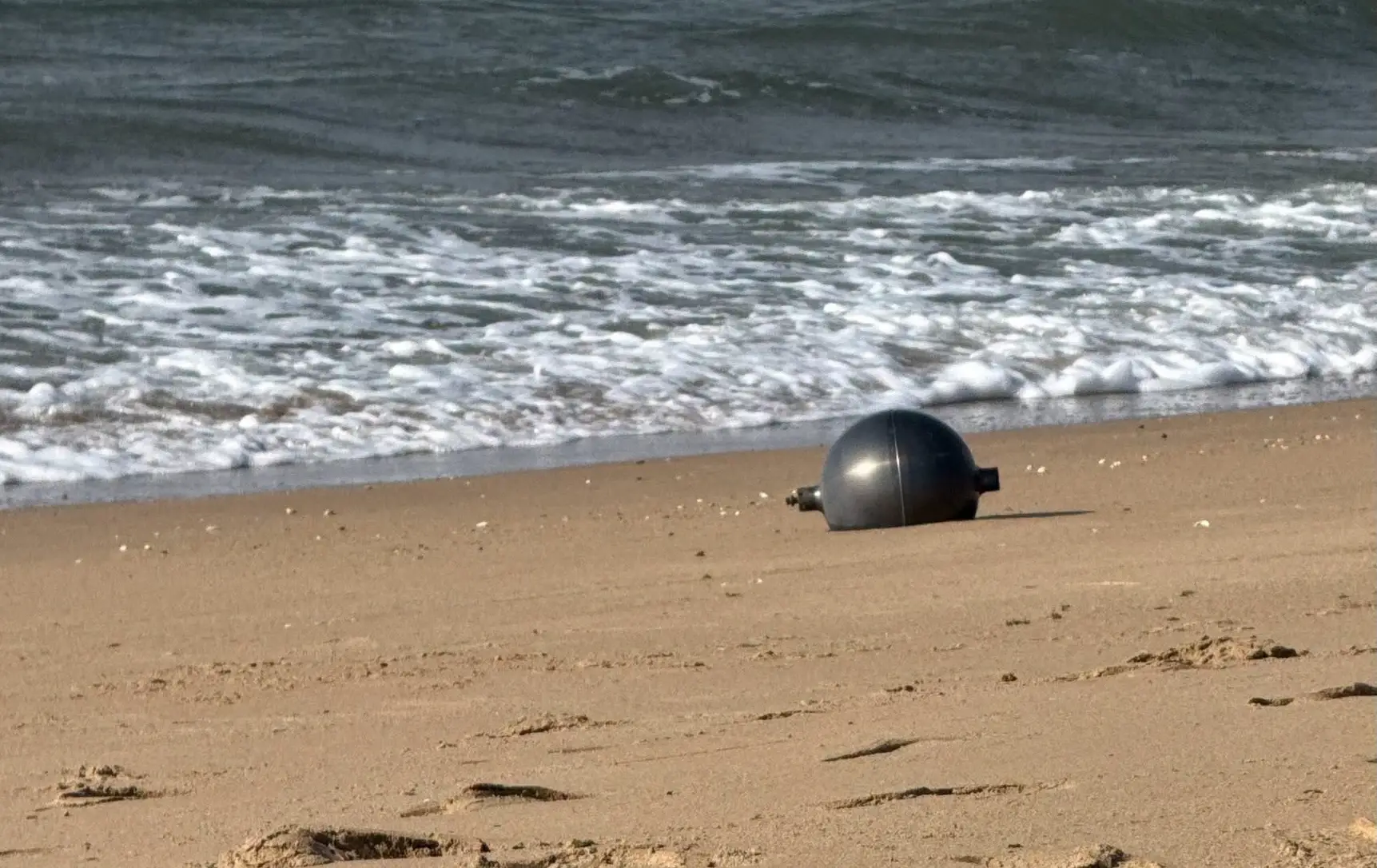 Six mysterious metallic orbs appeared on a secluded beach in Australia, with experts weighing in on their origins (Facebook/Queensland Fire Department)