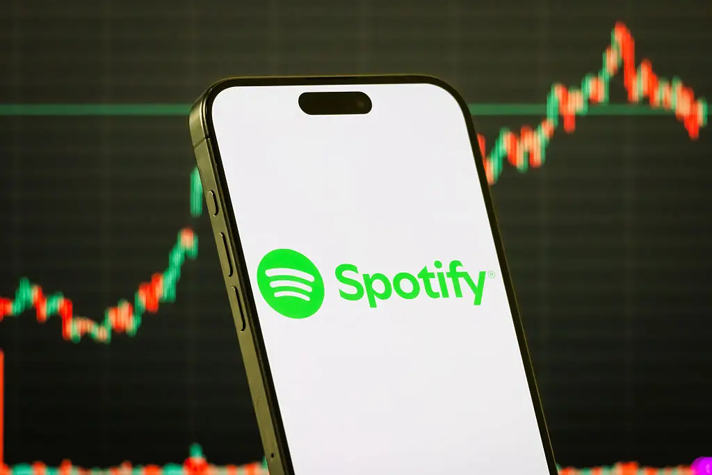 Spotify logo on smartphone with stock market chart background (Getty Images)